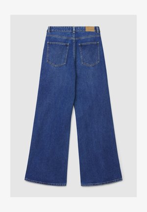 Jeans larghi in denim blu con vita alta, due tasche posteriori e toppa in pelle marrone sulla cintura. Tessuto liscio e cuciture robuste.