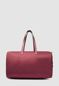 Bolsa de lona grande en color granate con dos asas largas y cierre de cremallera lateral, mostrada sobre un fondo gris claro.