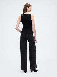 Top preto canelado sem mangas combinado com calças largas pretas e saltos agudos pretos. Textura suave e design ajustado.