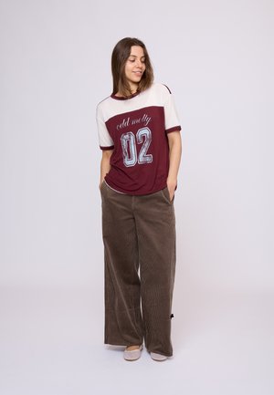 Bordeaux en crème T-shirt met korte mouwen met de print "cold molly 02" gecombineerd met brede, gestructureerde bruine corduroy broek. Heeft een relaxte pasvorm.