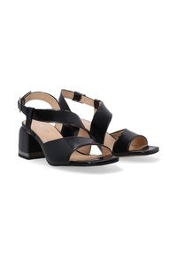 Schwarze Absatzsandalen verfügen über ein elegantes Obermaterial aus Leder mit einem Kreuzriemen-Design, offenen Zehen und einem klobigen Absatz für mehr Halt.