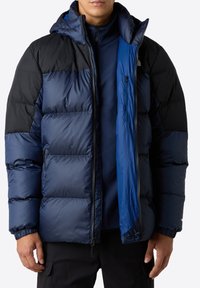 Mörkblå överdragsjacka med svart övre del och huva, med dragkedjestängning, elastiska mudd och quiltat mönster för isolering.