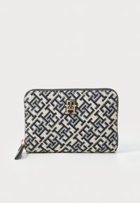Navy and cream patterned wallet with a zip closure, featuring a gold logo accent and a textured fabric surface. Rectangular shape.