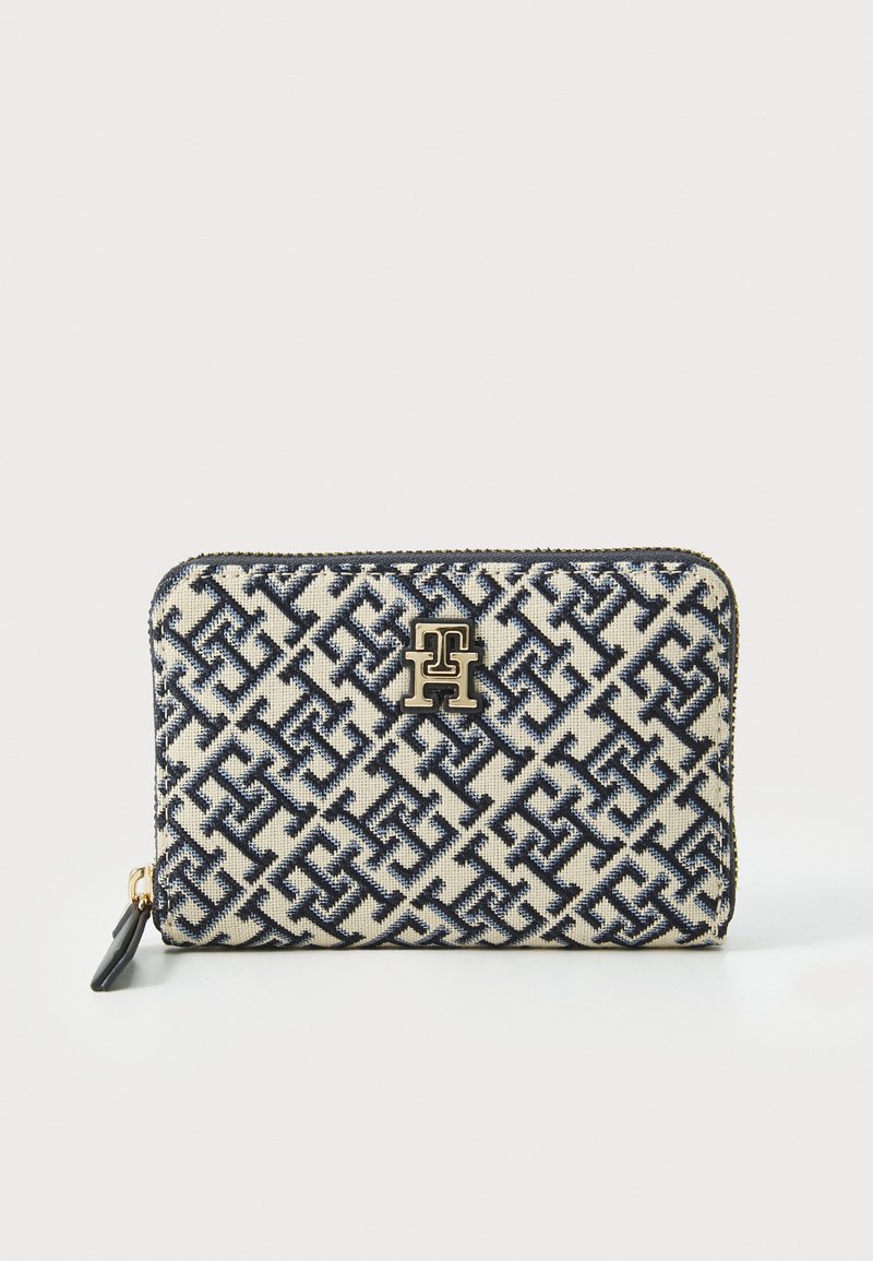 Navy and cream patterned wallet with a zip closure, featuring a gold logo accent and a textured fabric surface. Rectangular shape.