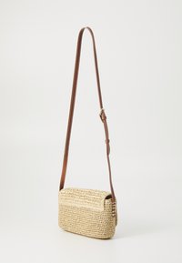 Woven straw purse with a rectangular shape, light beige color, and brown adjustable leather strap. Features a flap closure and textured surface.