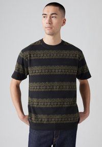 Camiseta de algodón negra con un patrón decorativo dorado en franjas horizontales. Escote redondo y mangas cortas, corte relajado.
