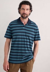 Polo à manches courtes en rayures teal et marine avec un col marine uni. Fabriqué en tissu texturé avec une coupe décontractée.