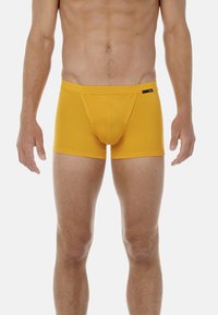 Boxer-briefs en coton jaune avec une coupe ajustée, comportant une poche de soutien et une ceinture lisse, mise en valeur par un petit logo noir.