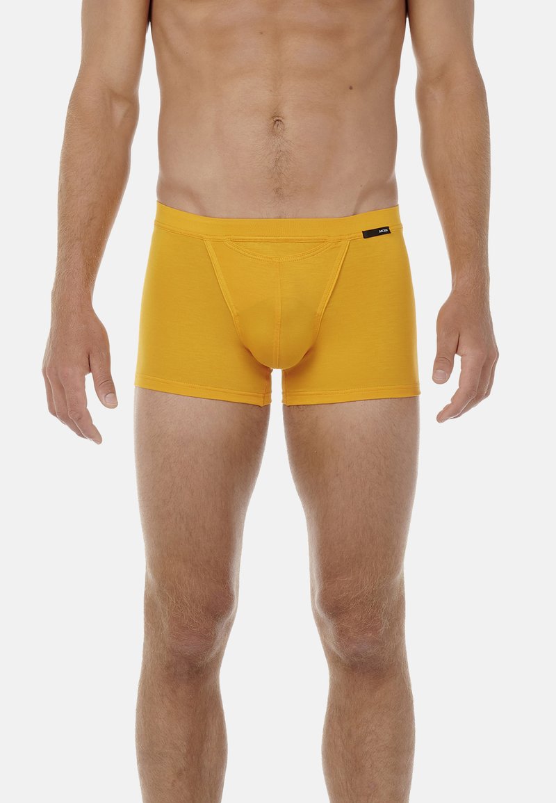 Boxer-briefs en coton jaune avec une coupe ajustée, comportant une poche de soutien et une ceinture lisse, mise en valeur par un petit logo noir.