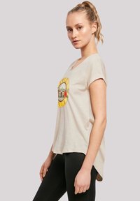 Beige short-sleeve t-shirt with a rounded neckline. Features a colorful graphic design on the front. Worn with black leggings.