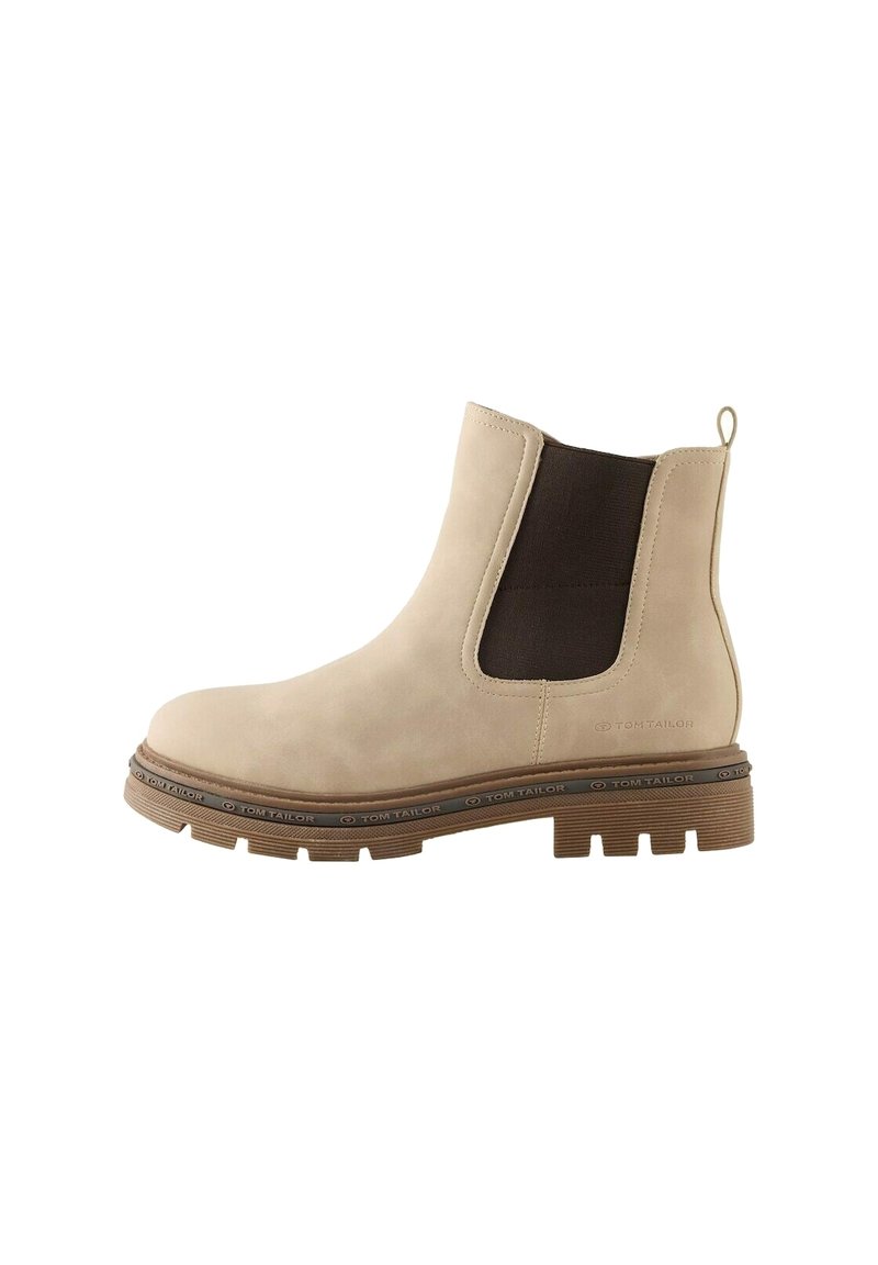 Botte cheville en daim beige avec des panneaux latéraux élastiques foncés, une languette de tirage et une semelle en caoutchouc robuste, présentant un accent de marque autour de la base.