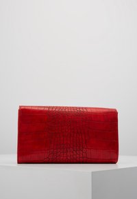 Clutch in finta pelle di coccodrillo rossa con una finitura texturizzata, forma rettangolare e un esterno liscio. Presenta una chiusura a patta senza hardware visibile.