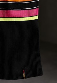 Robe noire côtelée avec des rayures horizontales colorées en orange, rose et jaune, ornée d'une étiquette logo "SUPERDRY" sur l'ourlet inférieur.