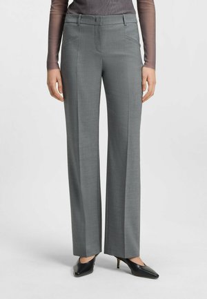 Pantaloni grigi su misura con una texture liscia, frontale piatto e tasche laterali. Abbinati a scarpe nere con tacco alto per un look formale.