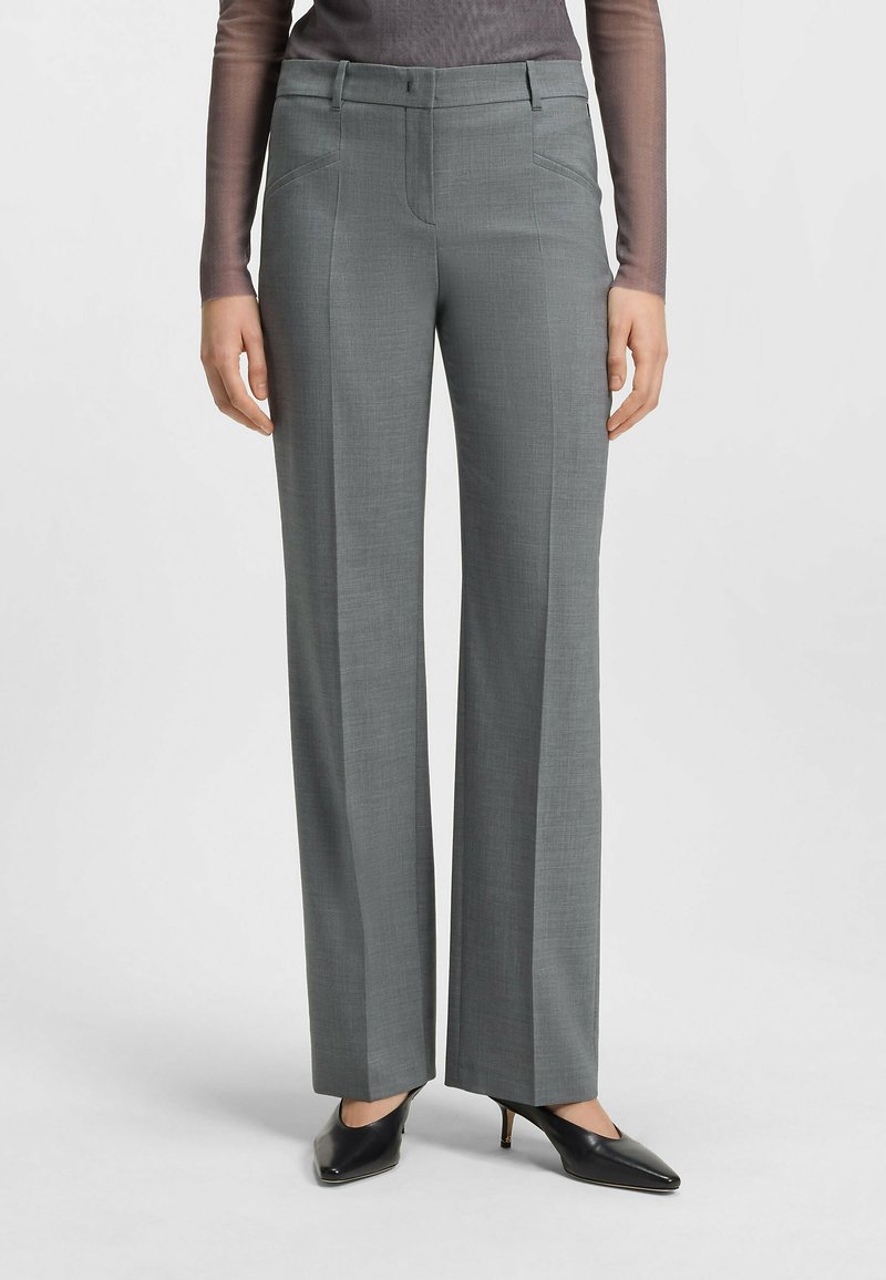 Grau maßgeschneiderte Hose mit glatter Textur, flacher Front und seitlichen Taschen. Kombiniert mit schwarzen High-Heels für einen formellen Look.