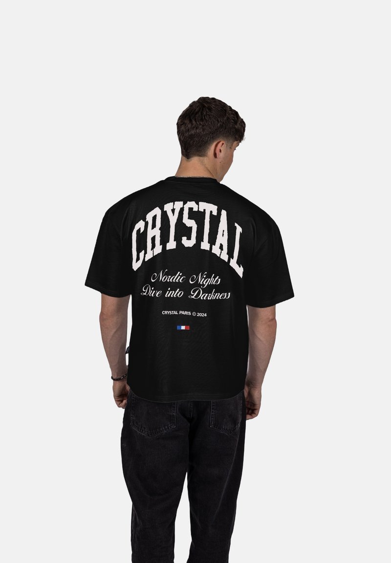 Černé oversized tričko s nápisem "CRYSTAL" velkým bílým písmem na zadní straně, která obsahuje text a logo "Nordic Nights Dive into Darkness".