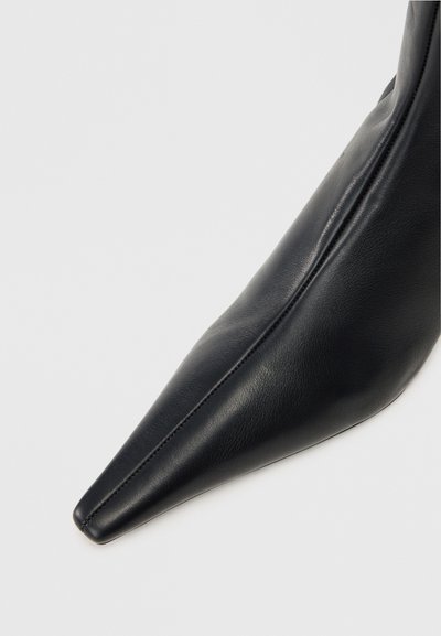 Juodas odinis aulinukas iki kulkšnies su smailiu nose ir lygiu paviršiumi. Yra elegantiškas dizainas ir siuvinėjimas šone.