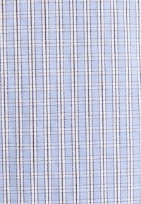 Tissu bleu clair avec des rayures verticales et horizontales foncées et blanches formant un motif à carreaux fin.