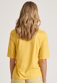 Korte mouwen gele t-shirt gemaakt van een gladde stof, met een relaxed fit, ronde halslijn en eenvoudig ontwerp, gecombineerd met gestreepte shorts.