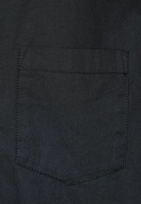 Schwarzer Stoff mit einer glatten Textur weist eine aufgesetzte Tasche auf. Die Tasche hat eine rechteckige Form und ist mit kontrastierendem Nähten eingefasst.