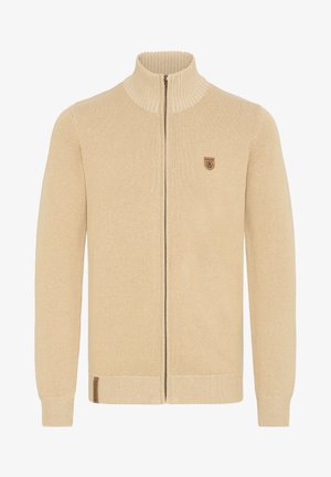 Bežinė užtrauktuku užsegama megzta kardiganė su aukštu apykakle, raukšlėta tekstūra ir mažučiu emblem arba krūtinėje. Turinti pilno ilgio rankoves ir liemenį.