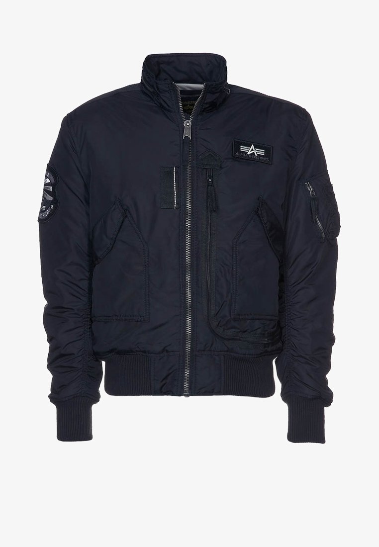 Veste bomber bleu marine avec fermeture éclair à l'avant, deux poches inclinées, poignets et ourlet côtelés, et patchs sur la poitrine et la manche gauche.