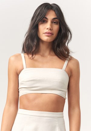Light beige linen crop top with thin straps, a straight neckline, and a fitted design, paired with a matching high-waisted skirt.