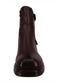 Botín de cuero burdeos con puntera redonda, textura lisa y detalle metálico lateral. Detalles de costuras a lo largo de la suela.