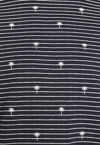 Granatowy materiał w białe poziome paski, z małymi białymi haftowanymi palmami w równych odstępach, miękka tekstura.