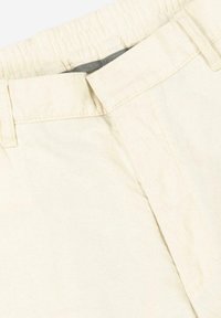 Light beige cotton shorts with an elastic waistband, flat front, and subtle texture. Features a concealed zipper and belt loops.