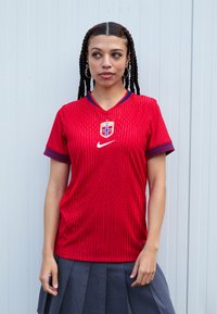 Red Nike jersey with vertical stripes, v-neck design, blue trim around sleeves, featuring a Norway crest and logo on the chest.