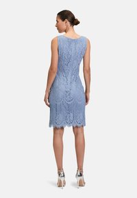 Robe en dentelle bleu clair avec une silhouette ajustée, sans manches, ourlet festonné et motif floral texturé. Fermeture éclair au dos.