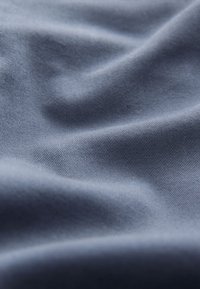 Blue fabric with a smooth texture and subtle sheen, featuring soft folds and creases that highlight its draping characteristics.