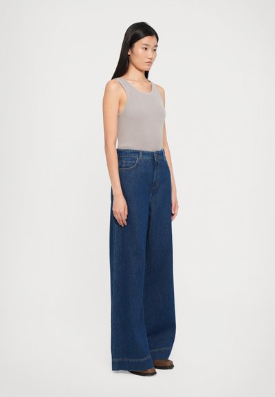 Light gray ribbed tank top paired with wide-leg dark blue denim jeans, featuring a high waist and subtle stitching details.
