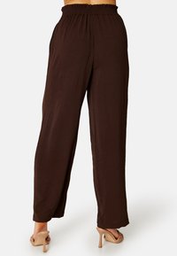 Bruine wijde broek met een elastische tailleband, gemaakt van een lichtgewicht textuurstof, met een vloeiende uitstraling en een relaxte pasvorm.