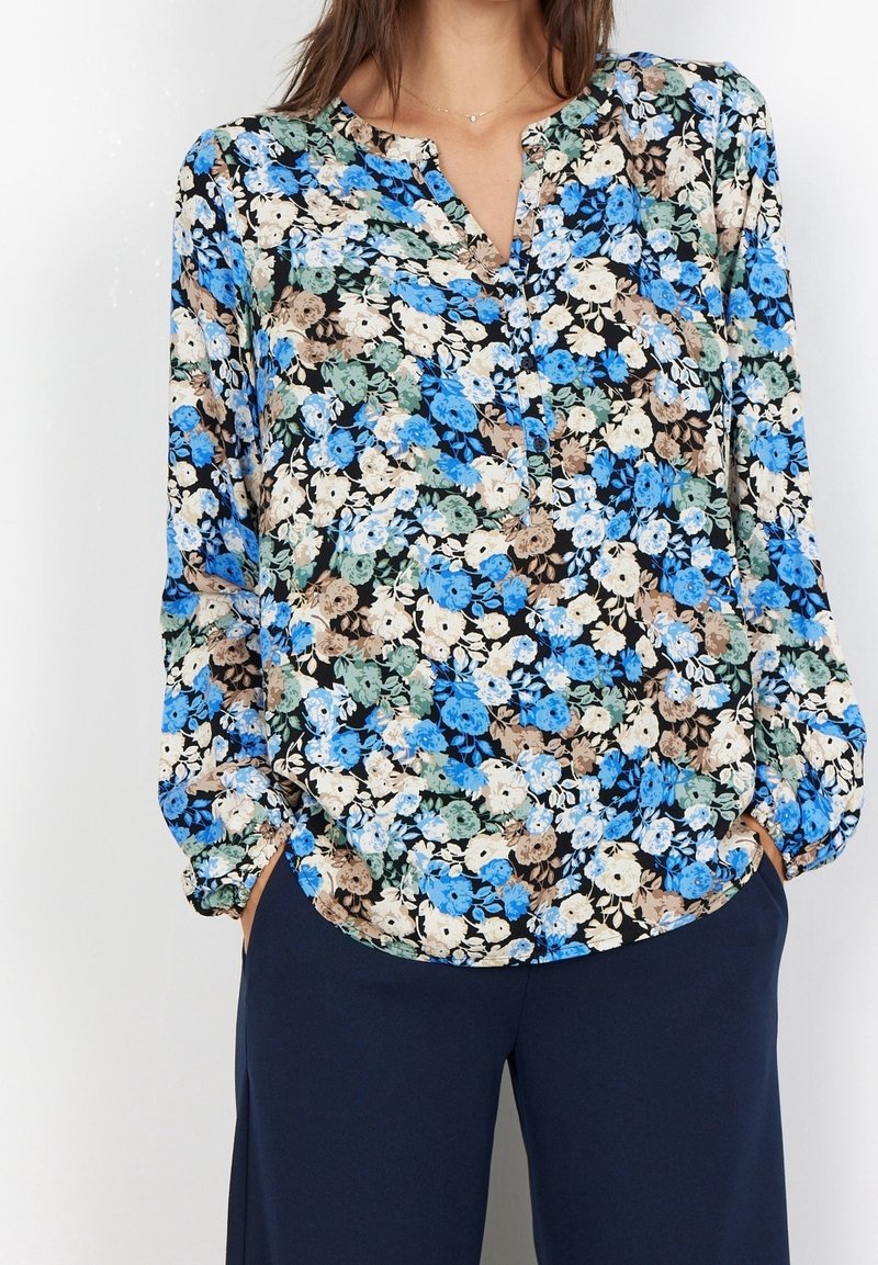 Blommig blus med svart bakgrund prydd med blå, gröna och beige blommor. Lättviktig tyg med v-ringning och långa, puffiga ärmar.