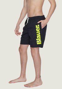 Pantaloni da nuoto neri con logo "Blauer." giallo neon sul lato, dotati di vita elastica e tasca laterale.