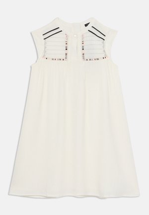 Witte mouwloze jurk met een getextureerde inzetstuk met verticale strepen en kleurrijke details, aangevuld met een ronde halslijn en knoopsluiting.