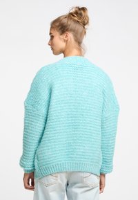 Helles blaues Strickpullover mit einer weichen, strukturierten Oberfläche. Verfügt über einen lockeren Schnitt, überschnittene Schultern und einen gerippten Saum. Rückansicht dargestellt.
