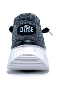 Sneaker texturé noir et gris avec une semelle blanche marbrée et des accents noirs. Présente un logo "HEY DUDE" à l'arrière.