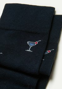 Navy Socken aus Baumwollmischung mit wiederholten hellblauen Cocktailglas-Mustern und roten Akzenten. Glatte Textur, gerippter Bund.