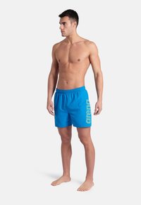 Pantaloni da nuoto blu con elastico in vita, caratterizzati da un grande logo "arena" sul lato. Tessuto morbido con vestibilità regolare.