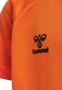 Orange idrottströja med ett texturerat mönster, korta ärmar och en svart "hummel"-logotyp på vänster sida.