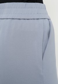 Lyseblå joggingbukser har en glat, blød tekstur, elastisk talje og sidelommer for funktionalitet.