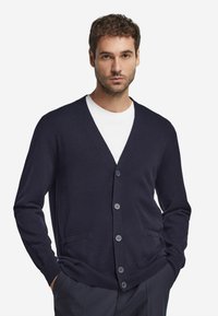 Mörkblå stickad cardigan med V-krage, fem knappar och två framfickor, med en mjuk textur och ribbade mudd och nederkant.