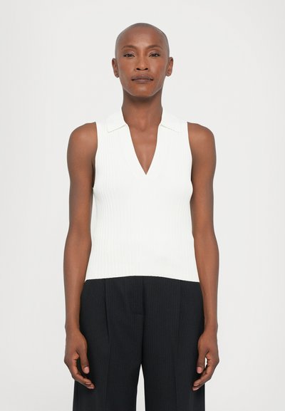 Witte geribbelde mouwloze top met een V-hals en kraag, gecombineerd met zwarte broek met streepjes. Gladde textuur, aansluitend ontwerp.