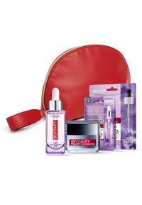 Trousse de maquillage rouge zippée avec des accents dorés contenant un sérum violet, un pot de crème et deux sachets de produit, tous étiquetés 'Revitalift Filler'.
