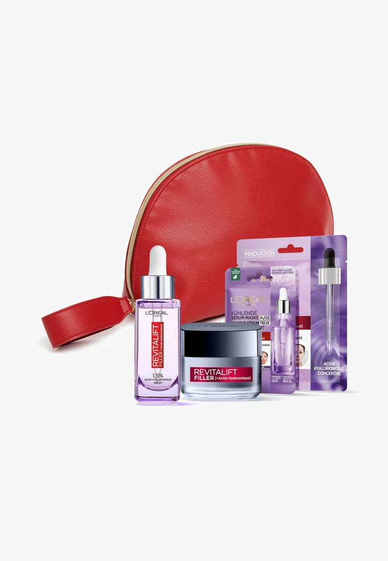 Trousse de maquillage rouge zippée avec des accents dorés contenant un sérum violet, un pot de crème et deux sachets de produit, tous étiquetés 'Revitalift Filler'.