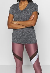 Grå kortärmad, v-ringad träningsskjorta kombinerad med rosa och svarta högmidjade leggings som har geometriska mönster och meshdetaljer.