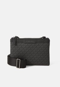 Black crossbody bag made of textured material with repeating logo pattern, features a zip closure and adjustable strap with a metal buckle.